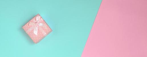 klein roze geschenk doos liggen Aan structuur achtergrond van mode pastel blauw en roze kleuren papier in minimaal concept foto