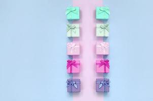 klein geschenk dozen van verschillend kleuren met linten leugens Aan een paars en roze achtergrond foto