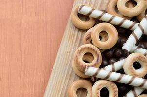 krokant buisjes, chocola smelten ballen en bagels liggen Aan een houten oppervlak. mengen van divers snoepgoed foto