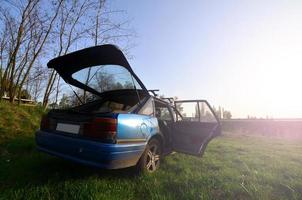 een blauw auto Aan een achtergrond van een rustiek landschap met een wild riet veld- en een klein meer. de familie kwam naar rust uit Aan de natuur in de buurt de meer foto