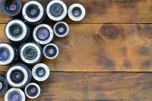 meerdere fotografisch lenzen liggen Aan een bruin houten achtergrond. ruimte voor tekst foto