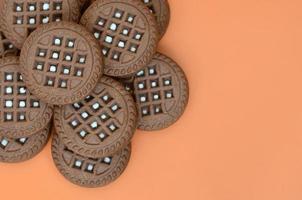 gedetailleerd afbeelding van donker bruin ronde belegd broodje koekjes met kokosnoot vulling Aan een oranje oppervlak. achtergrond beeld van een detailopname van meerdere behandelt voor thee foto