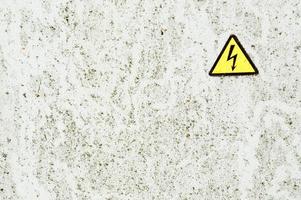 structuur van wit ijzer metaal roestig haveloos geschilderd verf spit muur en geel waarschuwing driehoekig Gevaar hoog Spanning teken. de achtergrond foto