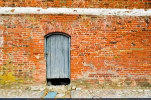 de structuur van de oud oude middeleeuws antiek solide houten natuurlijk dik deur met klinknagels en nagels patronen en sloten gemaakt van houten planken tegen de achtergrond van een steen muur van rood steen foto