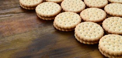 een ronde belegd broodje koekje met kokosnoot vulling leugens in groot hoeveelheden Aan een bruin houten oppervlak. foto van eetbaar behandelt Aan een houten achtergrond met kopiëren ruimte