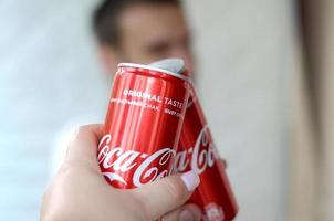 Charkov. Oekraïne - mei 2, 2019 gelukkig jong Mens verhogen Coca Cola blik kan met vrouw vriend in garage interieur foto