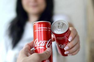 Charkov. Oekraïne - mei 2, 2019 gelukkig vrouw verhogen Coca Cola blik kan met mannetje vriend in garage interieur foto