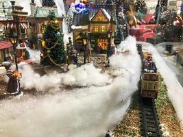 nieuw jaar landschap. miniatuur voor de vitrine. Kerstmis bomen zijn versierd voor de nieuw jaar met gouden slingers en ballen. De volgende naar een speelgoed- spoorweg met met sneeuw bedekt rails foto