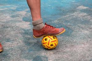 jong zuidoosten Aziatisch mannetje sepak takraw speler gebruik makend van zijn Rechtsaf enkel naar houden bal omhoog Aan de portie centrum Oppervlakte van de rechtbank, buitenshuis sepak takraw spelen na school, zacht en selectief focus. foto