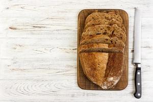 gesneden wit brood Aan snijdend bord Aan wit houten backgroound foto