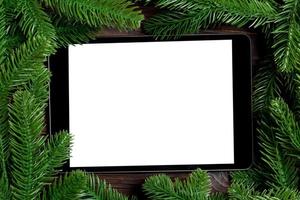 top visie van tablet versierd met een kader gemaakt van Spar boom Aan houten achtergrond. nieuw jaar tijd concept foto