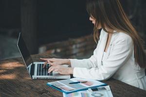 jong Aziatisch zakenvrouw werken Aan laptop computer met financieel grafieken grafieken , gebruik makend van bedrijf account software voor gegevens analyse en project beheer concept. foto