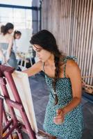 jong vrouw artiest verven met een spatel Aan de canvas foto