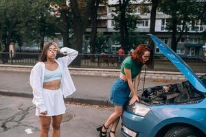 twee Dames met gebroken auto Aan de weg. Open kap foto