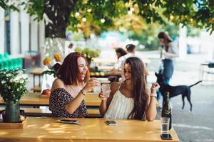 twee jong mooi Dames vriendinnetjes pratend in een buitenshuis cafe foto