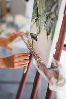 detailopname van een vrouw hand- toepassen verf naar een canvas foto