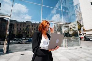 glimlachen vrouw op zoek Bij haar laptop buitenshuis, modern levensstijl. foto