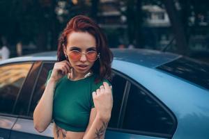 mooi modieus jong vrouw in bril poseren in de buurt auto foto