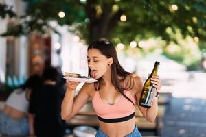 jong vrouw draagt een bord van snacks en een drinken in handen foto