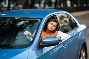 een jong boos vrouw gluurt uit van de auto venster foto