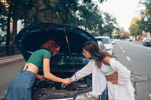 twee Dames met gebroken auto Aan de weg. Open kap foto