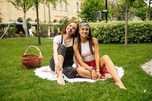 twee Dames hebben picknick samen, zittend Aan de plaid foto