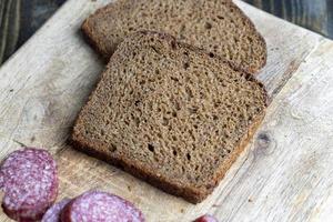 zwart rogge brood Aan een bord foto