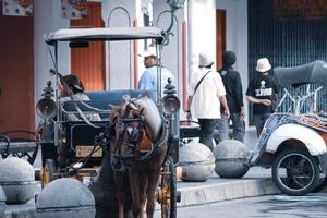 yogakarta, Indonesië Aan oktober 23, 2022. andong of door paarden getrokken vervoer met haar koetsier geparkeerd Aan jalan malioboro, aan het wachten voor passagiers. foto