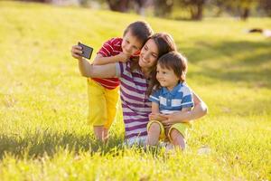 gelukkige moeder met twee kinderen, fotograferen in het park, foto