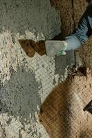 een Mens gooit beton Mortier Aan de muur, de eerste laag van gips Aan de muur, reparatie werk in Oekraïne. foto