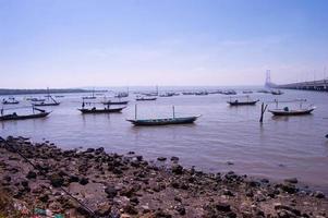 visie van de rotsachtig strand waar visvangst boten slank in kenjeran Surabaya foto