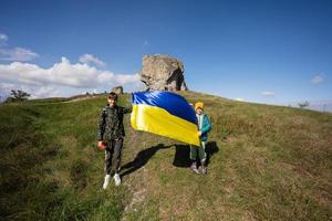 Welkom naar Oekraïne. twee broers houden oekraïens vlag in de buurt groot steen in heuvel pidkamin. foto