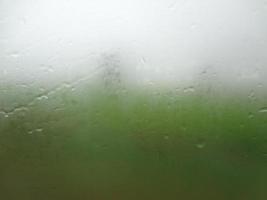 venster glas met condensatie hoog vochtigheid , groot druppels stromen naar beneden , groen natuurlijk water laten vallen achtergrond. foto