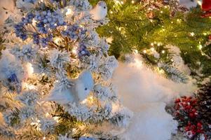 hoog kunstmatig sparren. de bomen zijn versierd met mooi, glimmend, kleurrijk ballen. vogelstand zijn zittend Aan de takken. sneeuw hangende Aan de takken foto