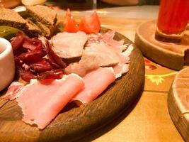 vlees tussendoortje met alcohol van vlees, ham, basturma met saus Aan houten staat Aan de tafel in een cafe, bar, restaurant foto