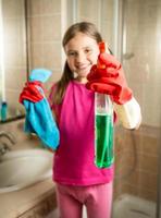 lachende meisje poseren met doek en reinigingsmiddel spray op badkamer foto