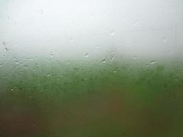 venster glas met condensatie hoog vochtigheid , groot druppels stromen naar beneden , groen natuurlijk water laten vallen achtergrond. foto