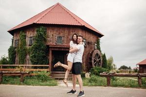 paar in liefde wandelingen in de buurt een groot houten molen Aan zomer dag. Mens en vrouw zijn hebben pret buitenshuis. foto