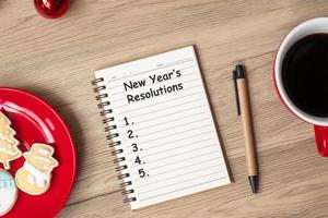 nieuw jaar resolutie met notitieboekje, zwart koffie beker, Kerstmis koekjes en pen Aan hout tafel. Kerstmis, gelukkig nieuw jaar, doelen, naar Doen lijst, strategie en plan concept foto