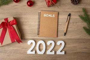 2022 doel met notitieboekje, Kerstmis geschenk en pen Aan hout tafel. Kerstmis, gelukkig nieuw jaar, oplossing, naar Doen lijst, begin, strategie en plan concept foto