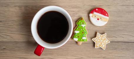 vrolijk Kerstmis met eigengemaakt koekjes en koffie kop Aan hout tafel achtergrond. Kerstmis vooravond, partij, vakantie en gelukkig nieuw jaar concept foto