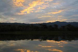silhouet van berg en reflectie van wolk in meer of rivier- met Woud en lucht achtergrond Bij zonsondergang of zonsopkomst tijd. schoonheid in natuur en natuurlijk behang. foto