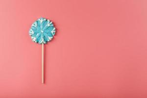 snoep in de vorm van een blauw sneeuwvlok Aan een roze achtergrond. foto