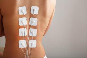 myostimulatie elektroden Aan een vrouw terug voor massage en revalidatie. foto