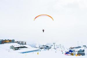 gudauri ski toevlucht panorama met tandem paragliders vlieg over- skiërs in ski toevlucht in verkoudheid winter dag foto