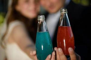 dichtbij omhoog glas flessen van verkoudheid oranje, rood en groen sap cocktail drankjes foto