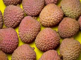 lychee op tafel. chinese pruim op een gele achtergrond. rijp fruit uit Azië. foto