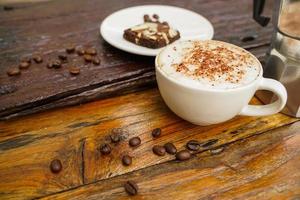 heet cappuccino in wit kop met houten achtergrond, koffie is een populair drinken allemaal over- de wereld. foto