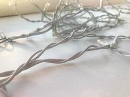 gedraaid wit draden van een slinger in wit rubber isolatie met licht bollen Aan een wit achtergrond foto