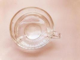 groot glas transparant mok met een omgaan met met schoon smakelijk drinken water Aan een roze achtergrond foto